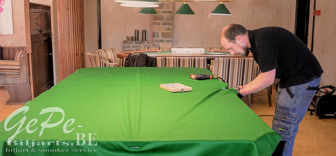 Gert aan het werk tijdens het vernieuwen van een snookerlaken op een klein model snooker
